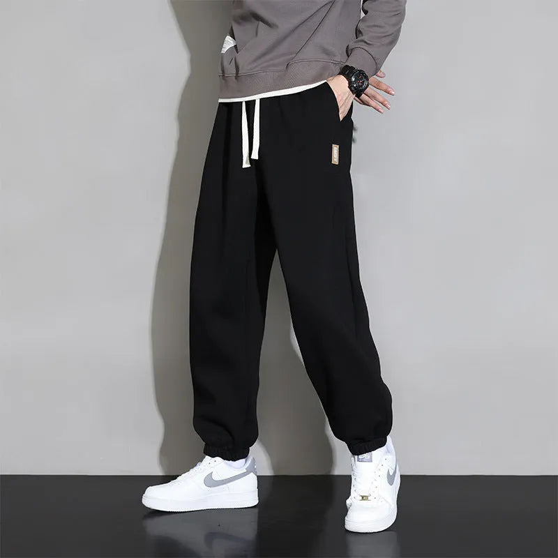 Men's loose grey casual sports trousers with drawstring waist on a plain background