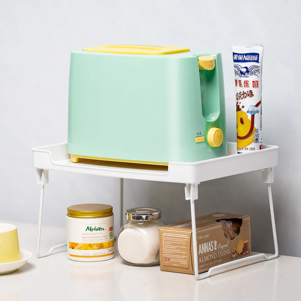 White plastic kitchen supplies rack on a countertop holding spice jars.