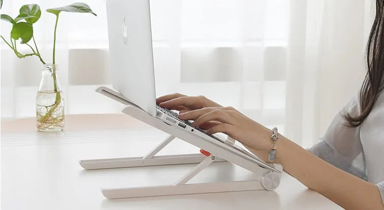 White foldable laptop bracket with heat sink base on a desk.