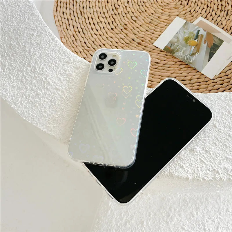 Transparent silicone iPhone case with laser-etched love heart design on a table.