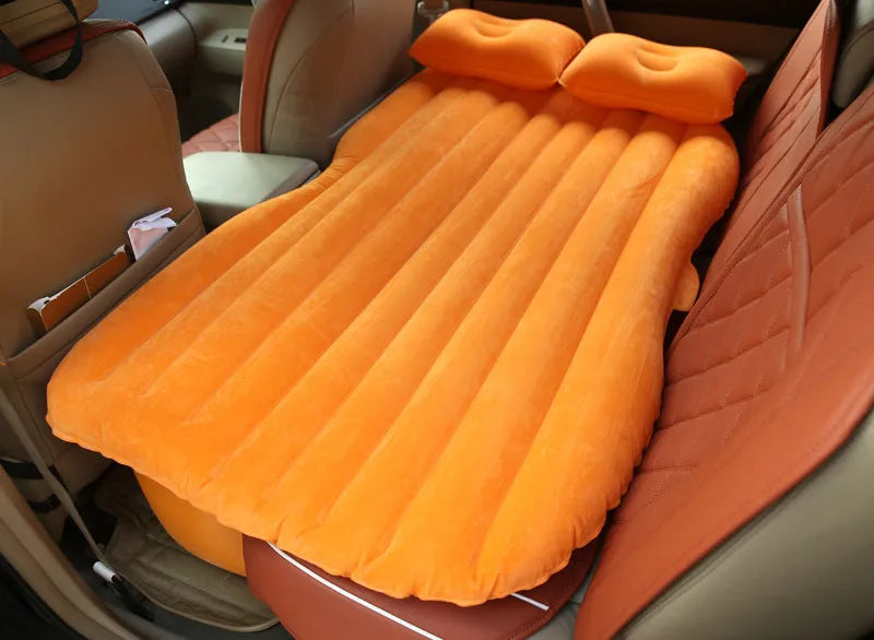 Universal inflatable car bed with flocked surface, shown with two pillows inside a vehicle.