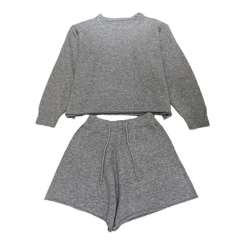 Woman wearing a loose grey long sleeve knitted sweater and matching wide leg shorts set.