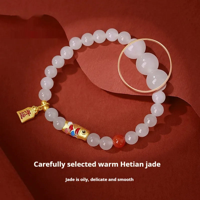 Close-up of a women's sterling silver bracelet with a koi fish cold enamel design and a natural Hetian jade component.