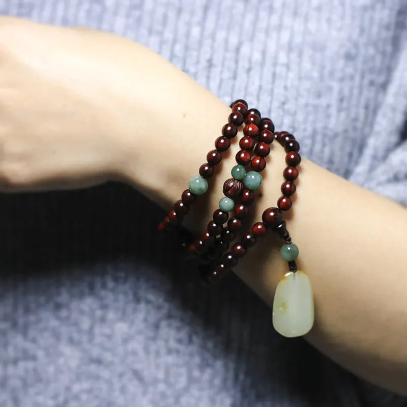 Carved rosewood bead bracelet with Hotian jade pendant showing wood grain texture