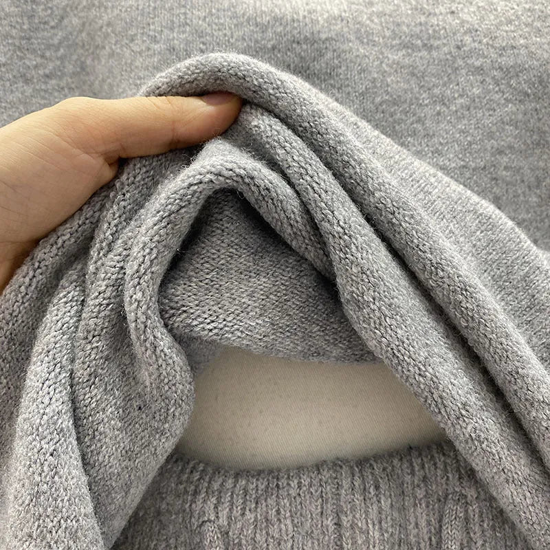 Woman wearing a loose grey long sleeve knitted sweater and matching wide leg shorts set.