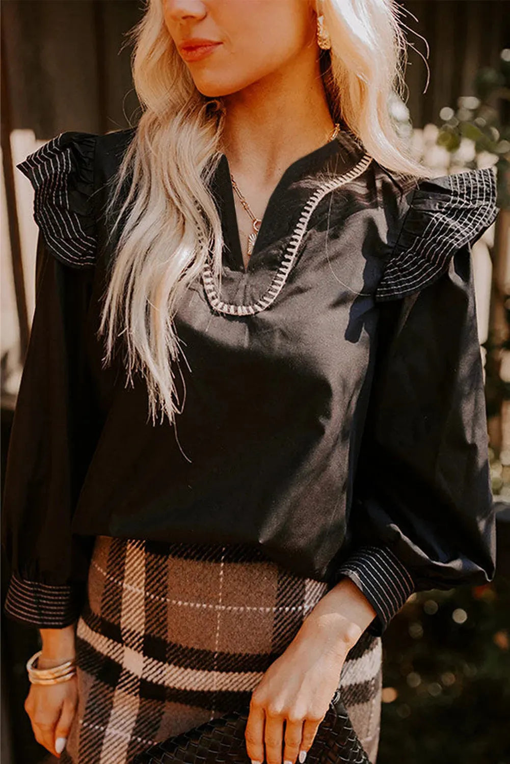 Black women's V-neck blouse with ruffle detailing on the long sleeves and contrast colour stitching.