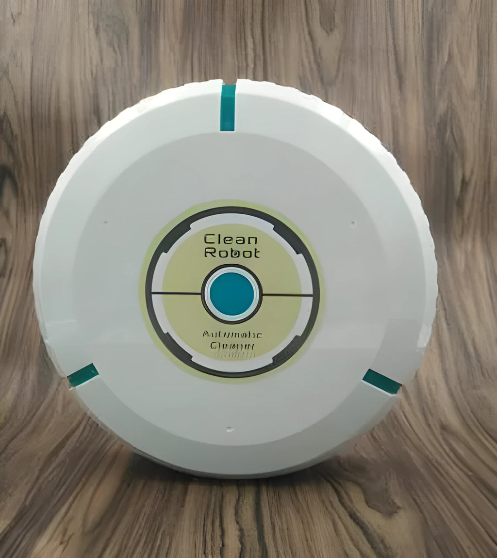 Black automatic sweeping robot on a wooden floor next to its packaging.