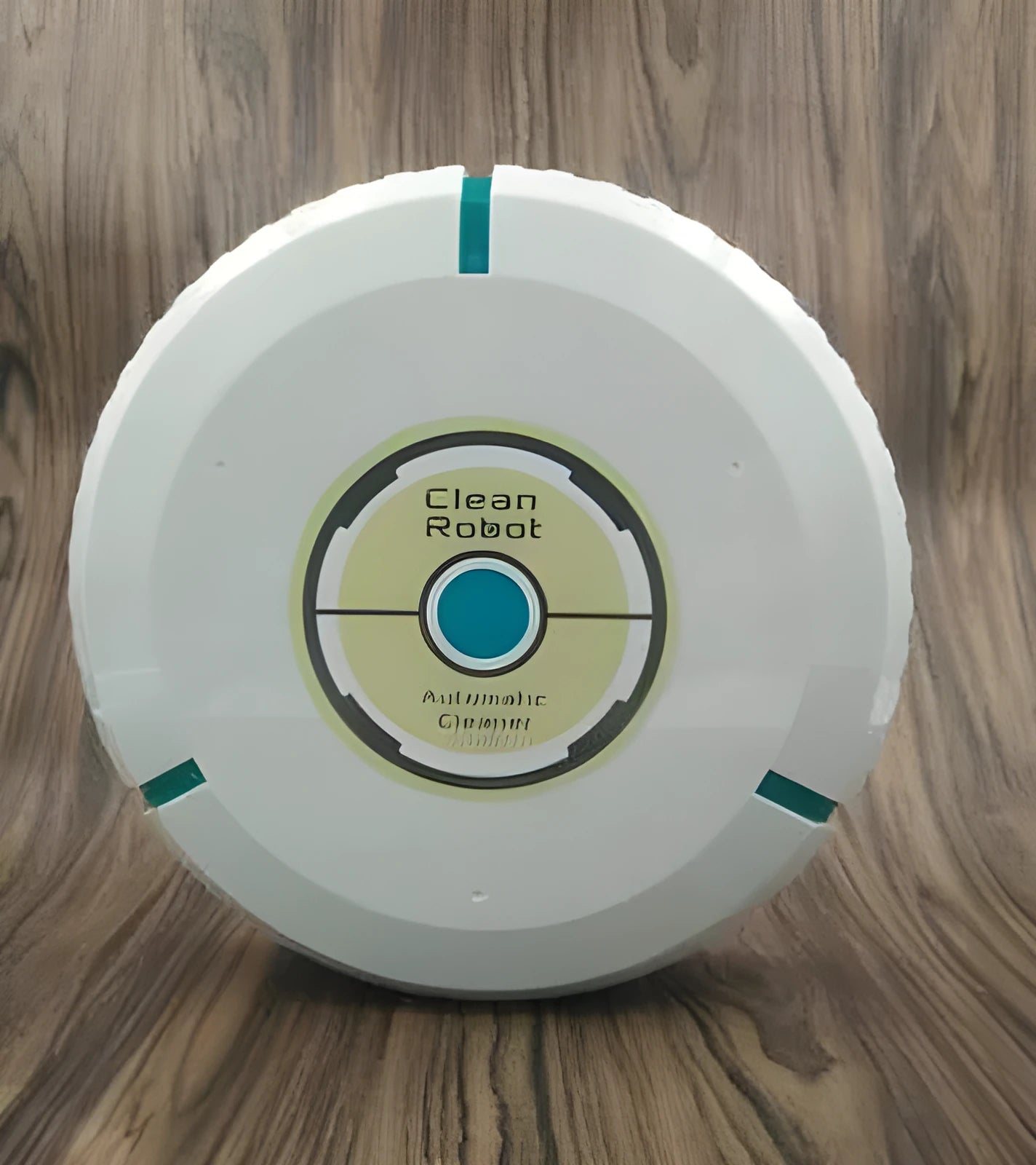 Black automatic sweeping robot on a wooden floor next to its packaging.