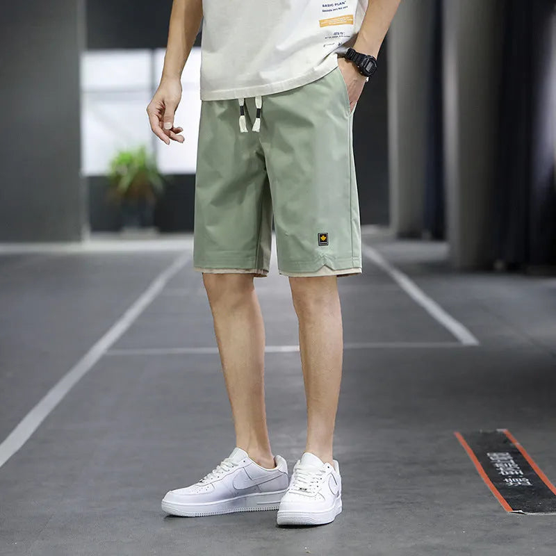 Man's loose fit casual shorts in green, shown flat, highlighting the straight cut and elastic waistband.