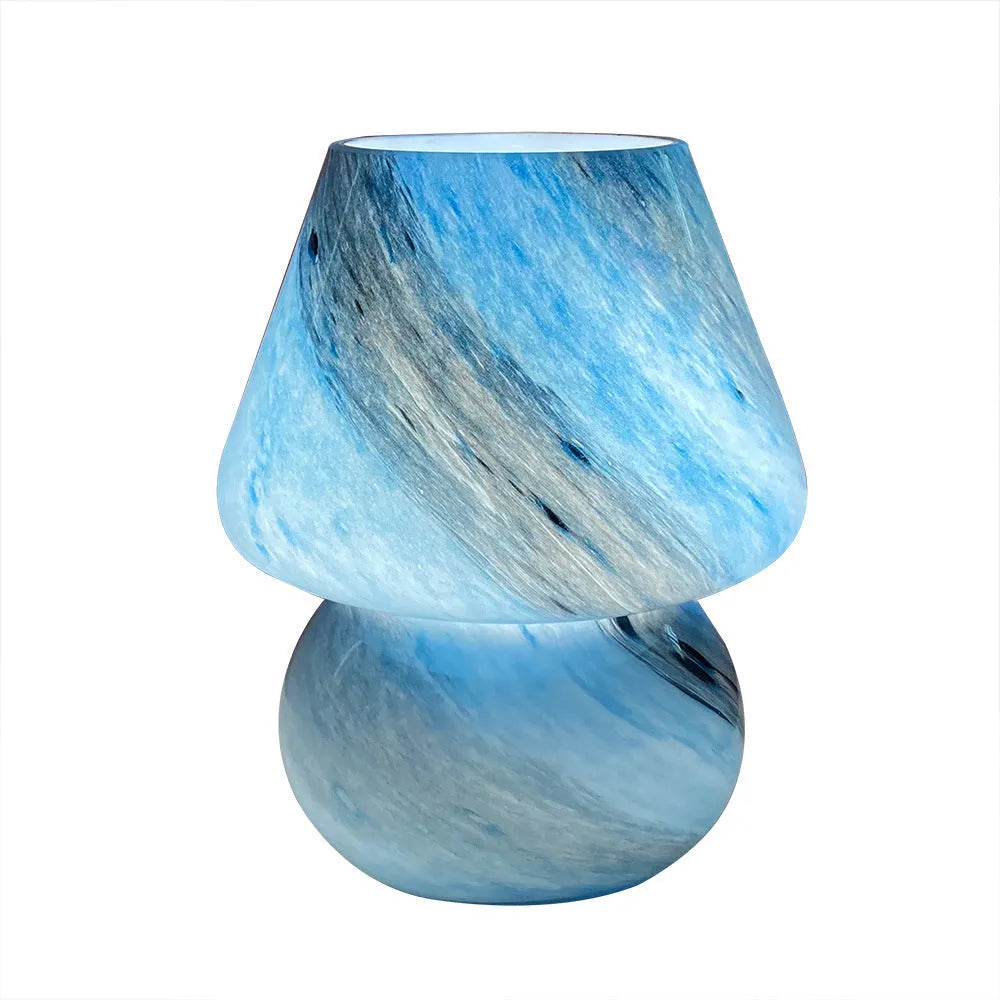 Handmade glass mushroom table lamp in colour finish, 15cm diameter, on a bedside table.