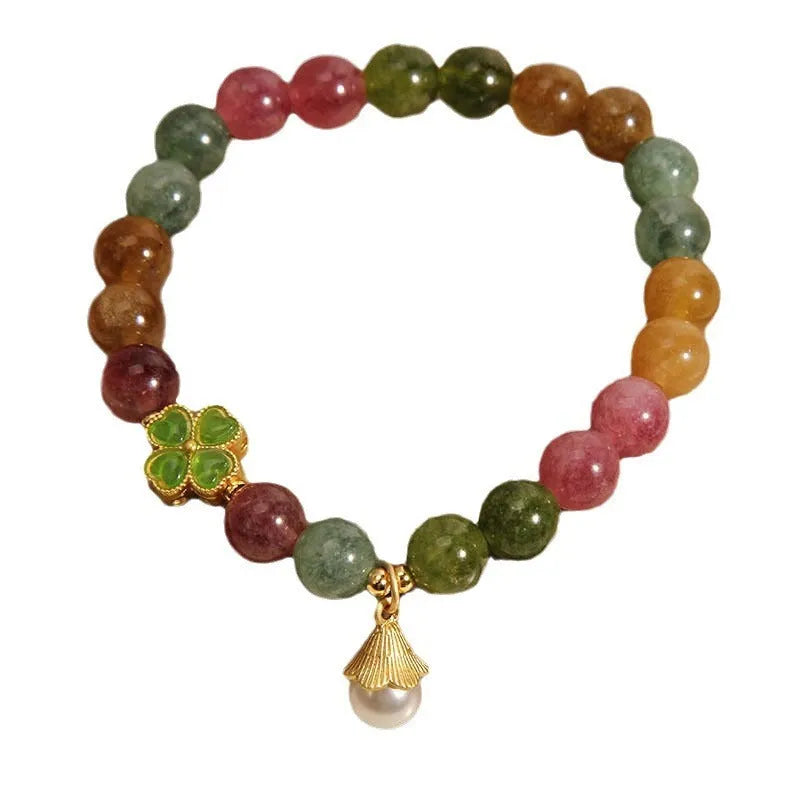 Natural colour tourmaline bracelet with four-leaf clover pearl pendant on wrist.