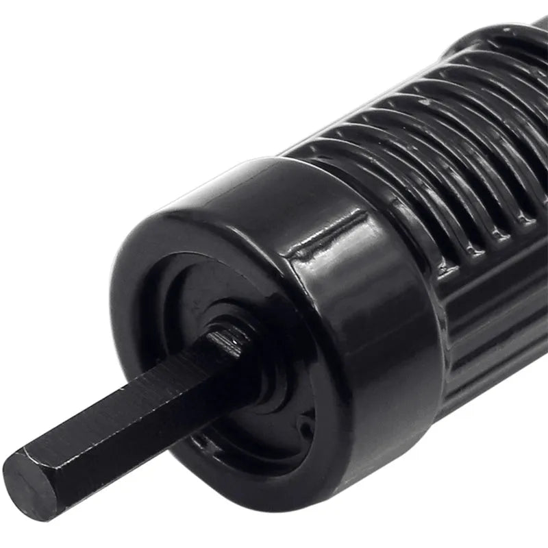 Black metal electric drill rivet gun adaptor with handle, wrench, and four rivet heads on a workbench.
