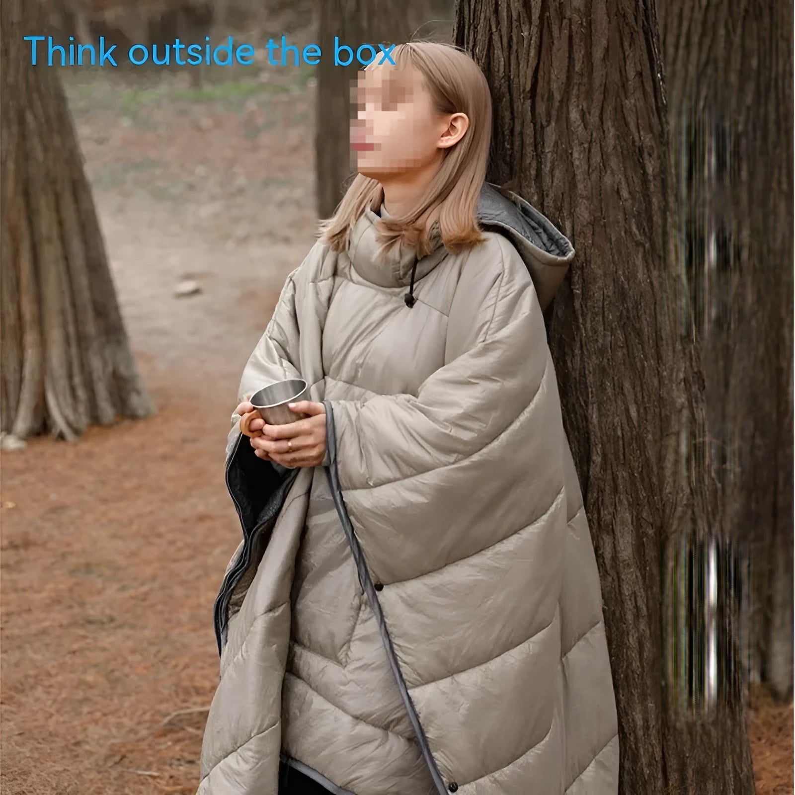 Grey outdoor cloak sleeping bag worn as a cape, showing its large 200x140cm size and hooded design.