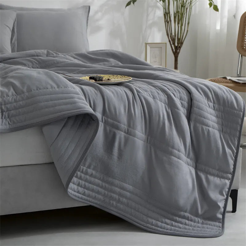 Plain colour seersucker summer cooling quilt shown in light pink on a bed.