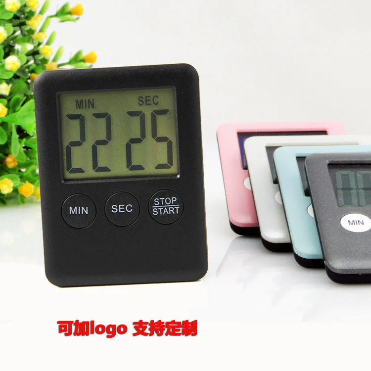 Black and white digital kitchen timer with LED display shown on a magnetic refrigerator door.