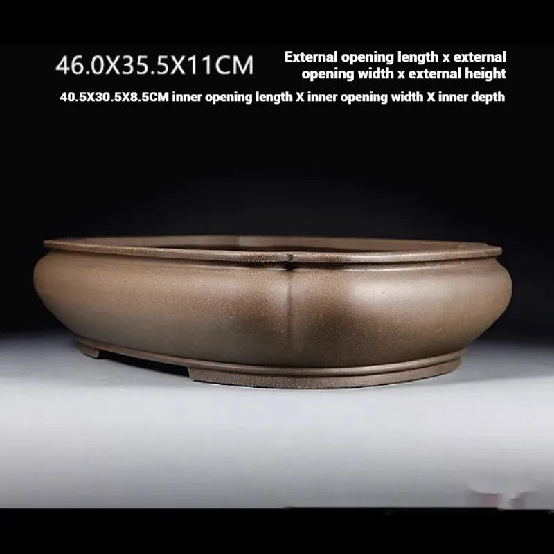Handmade antique papaya-shaped purple clay flower pot on a table.