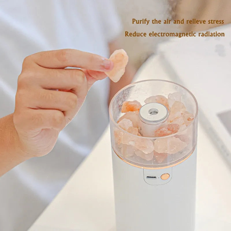 White desktop ultrasonic humidifier with crystal salt stone and LED lamp showing side view on table