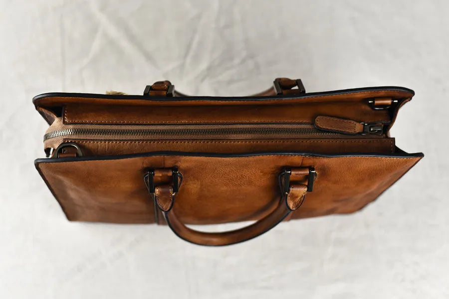 Men's brown leather retro style horizontal handbag with zipper, shown next to a 14-inch laptop for scale.