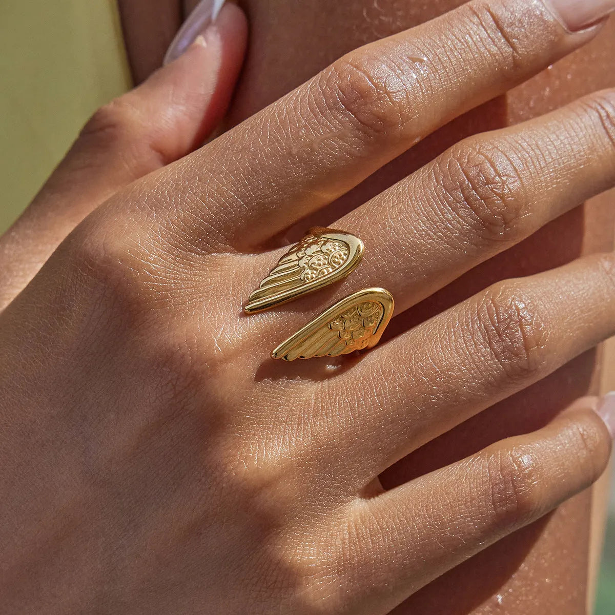 Stainless steel open-winged ring with electroplated colour on a grey background