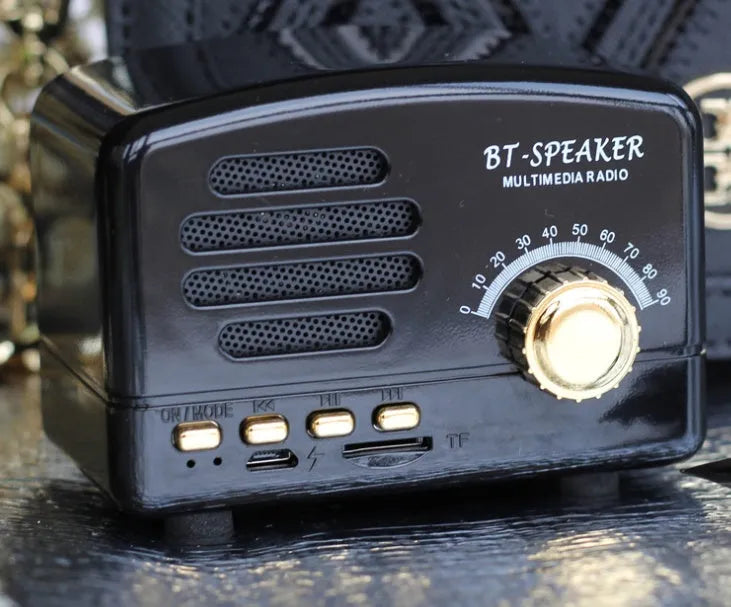 Compact vintage wood style Bluetooth speaker in pink, black, or wood grain finish on a table.