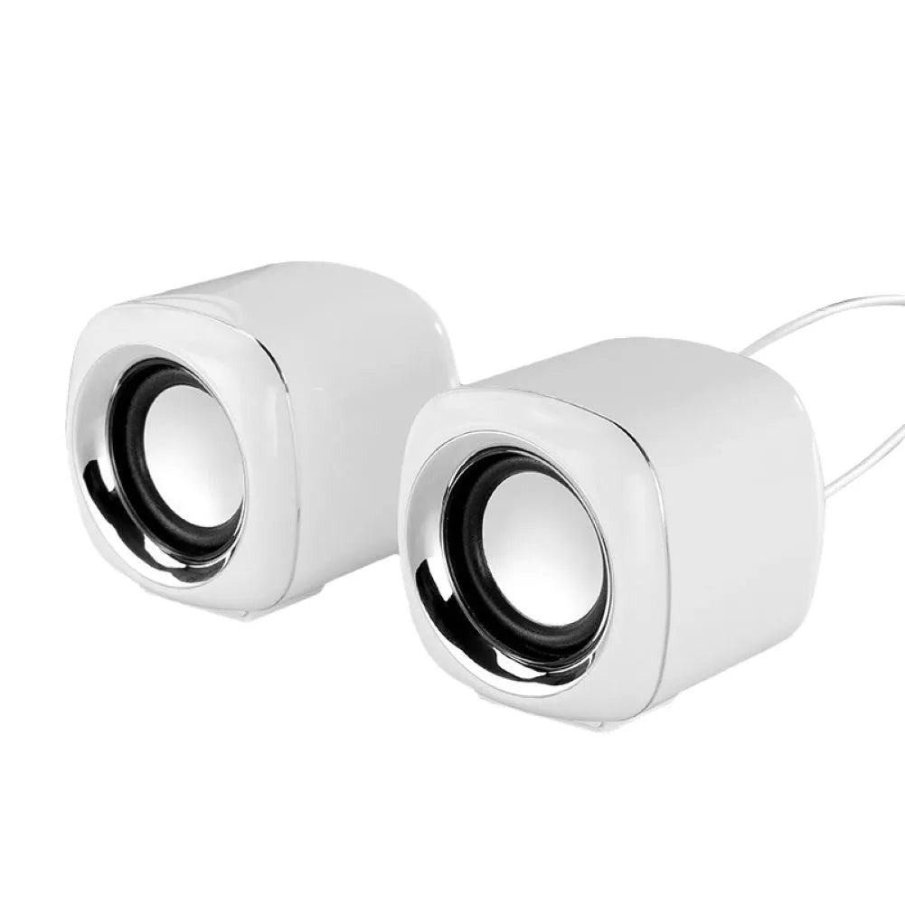 Pair of compact black wired desktop computer speakers with 3.5mm plug next to a laptop.