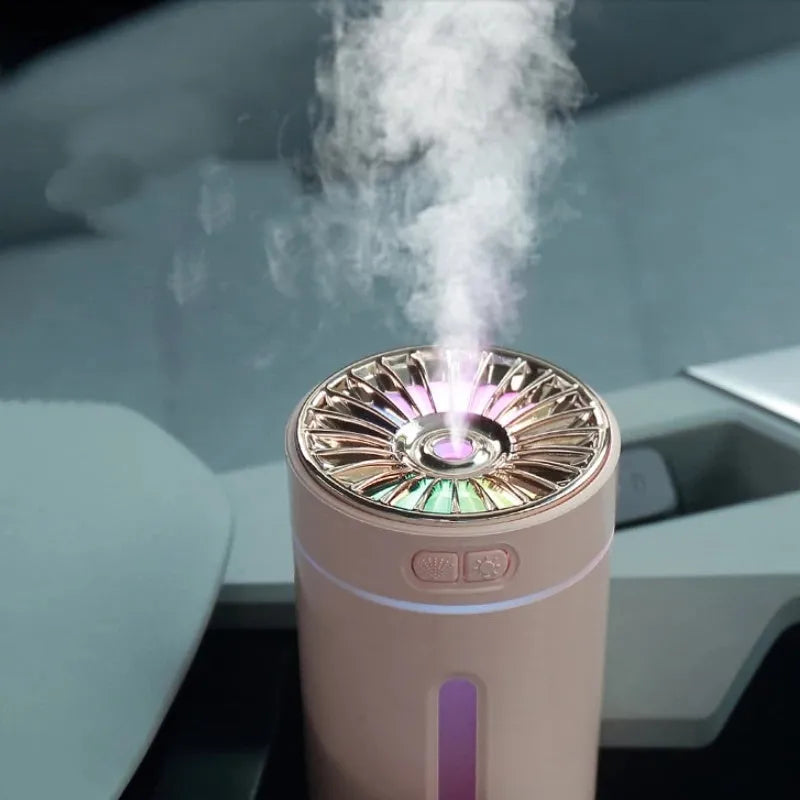 Black and white portable USB rechargeable car humidifier with colourful LED lights on a desk.