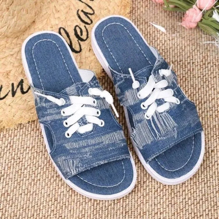 Blue women's flat canvas slippers with cloth lining and a rubber sole, shown in Roman style.