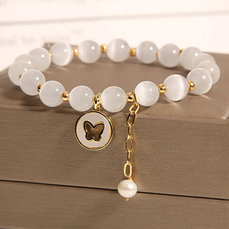 Close-up of a white cat's eye crystal bracelet with geometric links on a wrist.