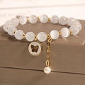 Close-up of a white cat's eye crystal bracelet with geometric links on a wrist.