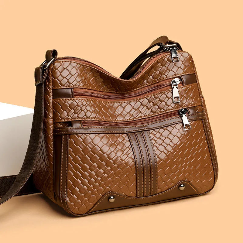 Horizontal square messenger bag with multiple compartments and woven shoulder strap in black with brown trim