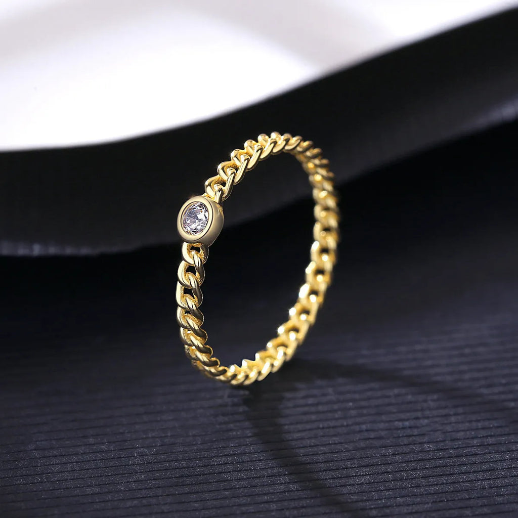 Close-up of 925 silver twist gold ring with geometric chain detail on a neutral background