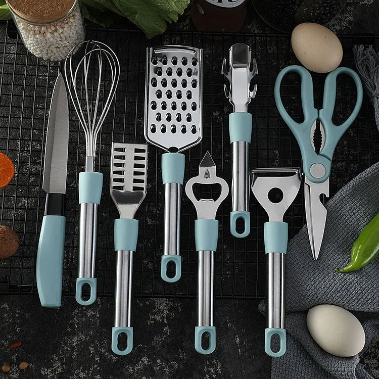 Stainless steel kitchen gadgets set with whisk, peeler, scissors, and fruit knife on grey tray