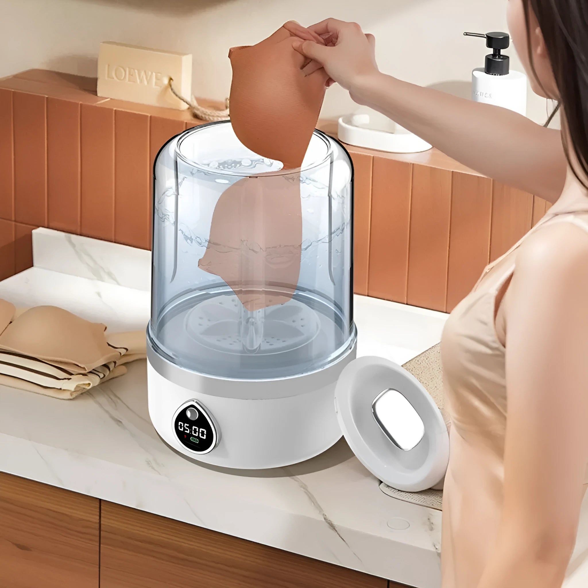 A compact white portable washing machine with USB cable on a countertop.