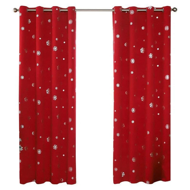Red snowflake pattern shade cloth curtain with iron hoops hanging on a rod against a window.