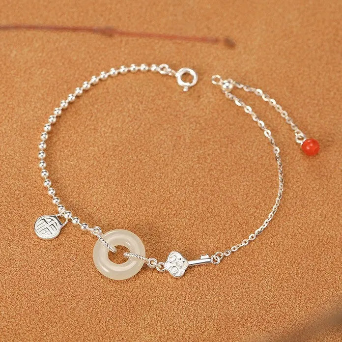 Women's silver bracelet with Hetian jade and a traditional Chinese peace buckle charm on a geometric link chain.