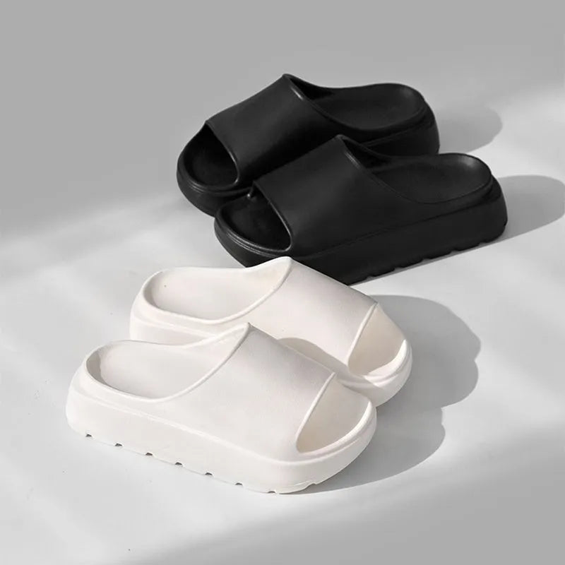 Women's beige open-toe beach slippers with a thick light-coloured sole on a wooden deck.