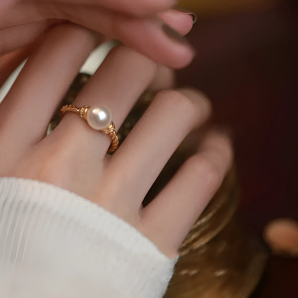 Geometric antique twist ring with a central pearl, on an adjustable copper band in gold colour.