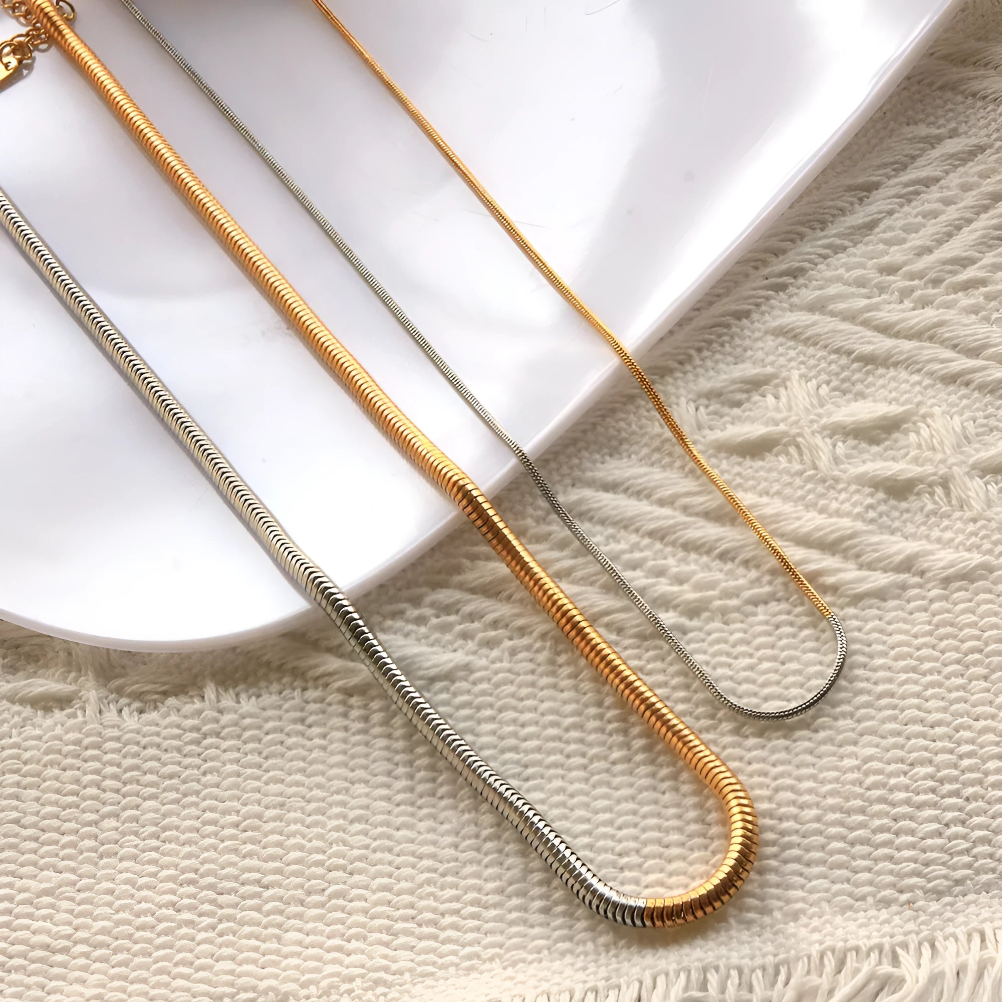 Close-up of a woman's golden 3mm wide snake bones chain necklace with geometric links.