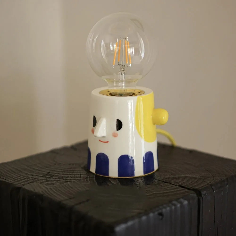 Handmade ceramic bedside lamp with ball headlight colour finish on a table.