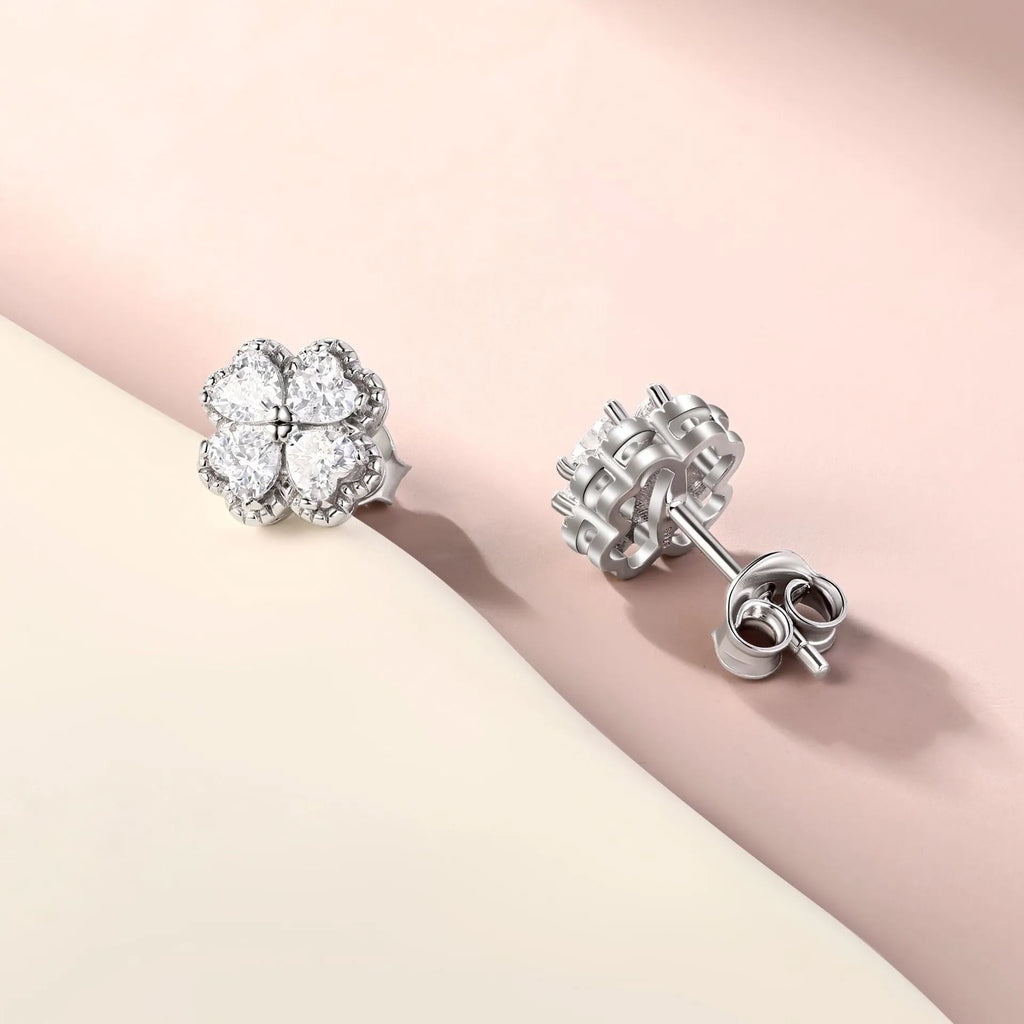 A pair of 925 silver earrings with a four-leaf clover charm and heart-shaped zircon stones in white gold colour.
