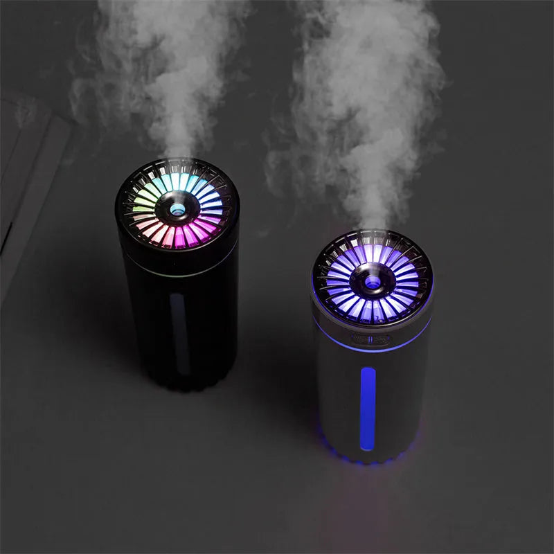 Black and white portable USB rechargeable car humidifier with colourful LED lights on a desk.