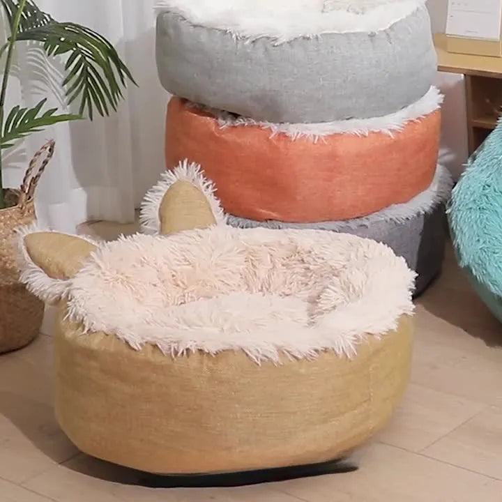 Blue plush faux fur circular cat bed with raised sides on a wooden floor