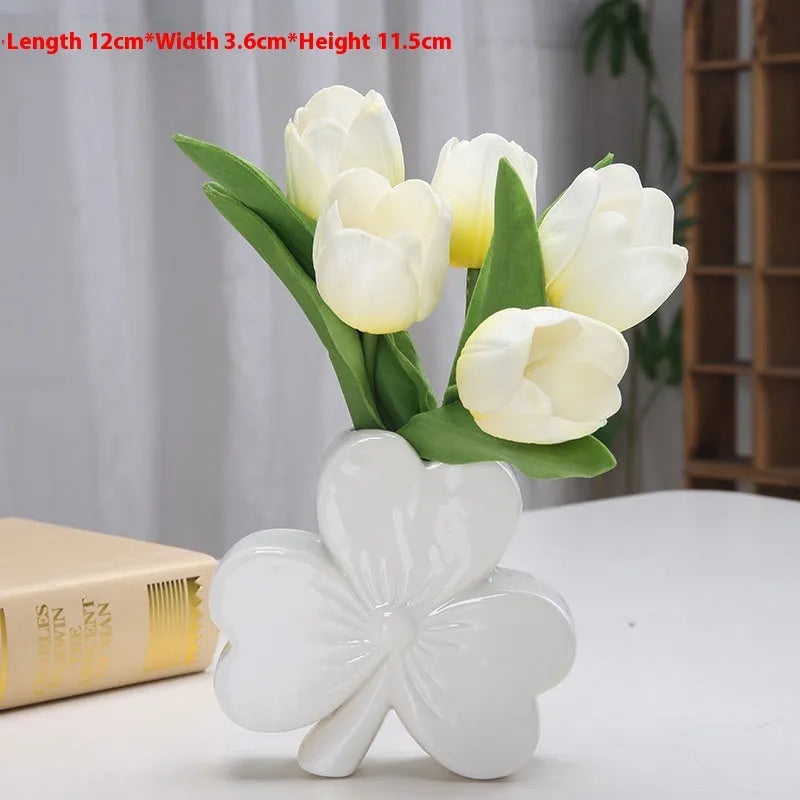 White porcelain clover-shaped ceramic vase on a desk, shown in light green colour.