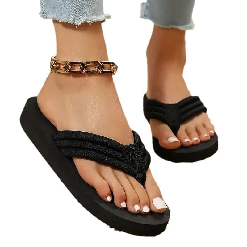 Black women's flat slippers with cotton upper and non-slip EVA sole on a beach background.