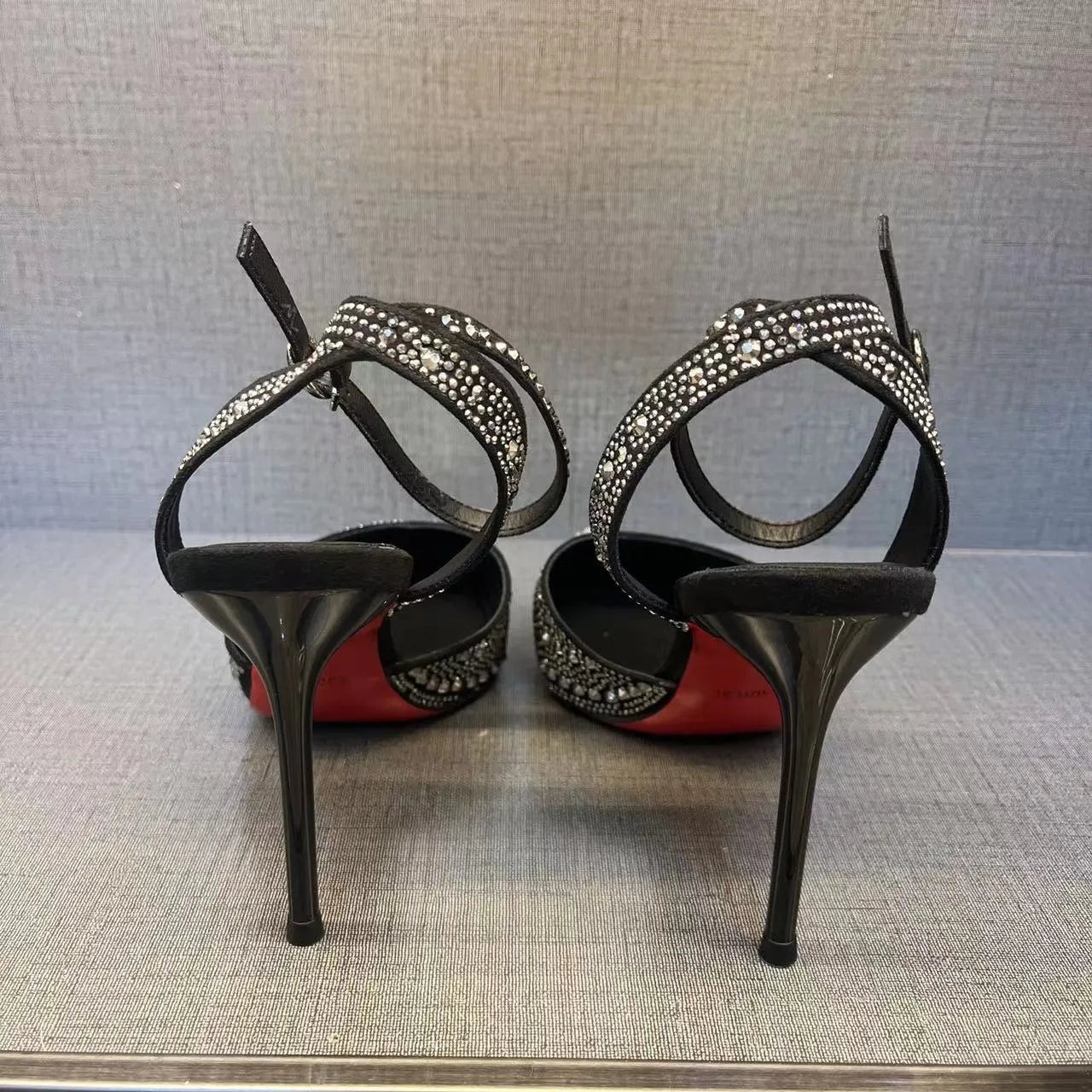 Women's black pointed toe stiletto heels with a hollow design and red sole.