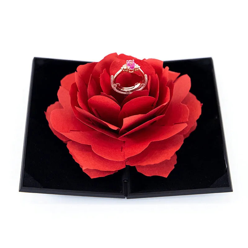 Red 3D heart-shaped plastic ring box with a rotating white rose decoration on top.