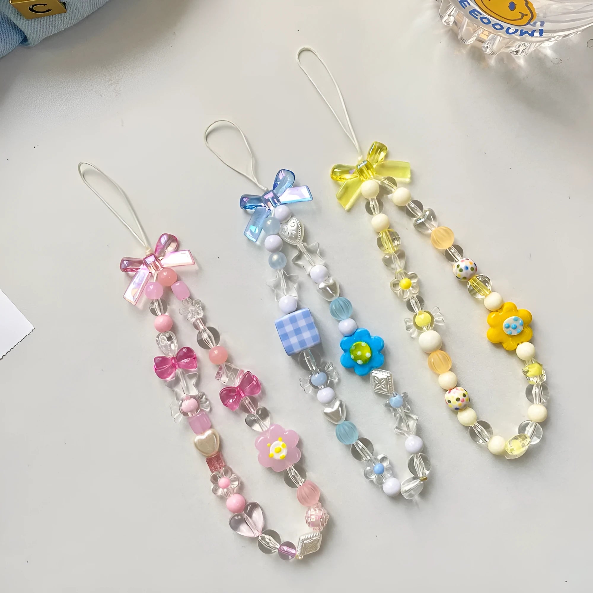 Colourful beaded flower mobile phone lanyard with a hand rope loop in blue, pink, or yellow.