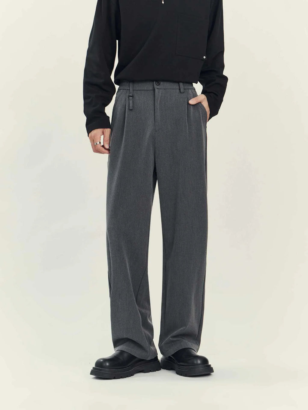 Man wearing loose straight-leg black business casual trousers made from polyester blend fabric.