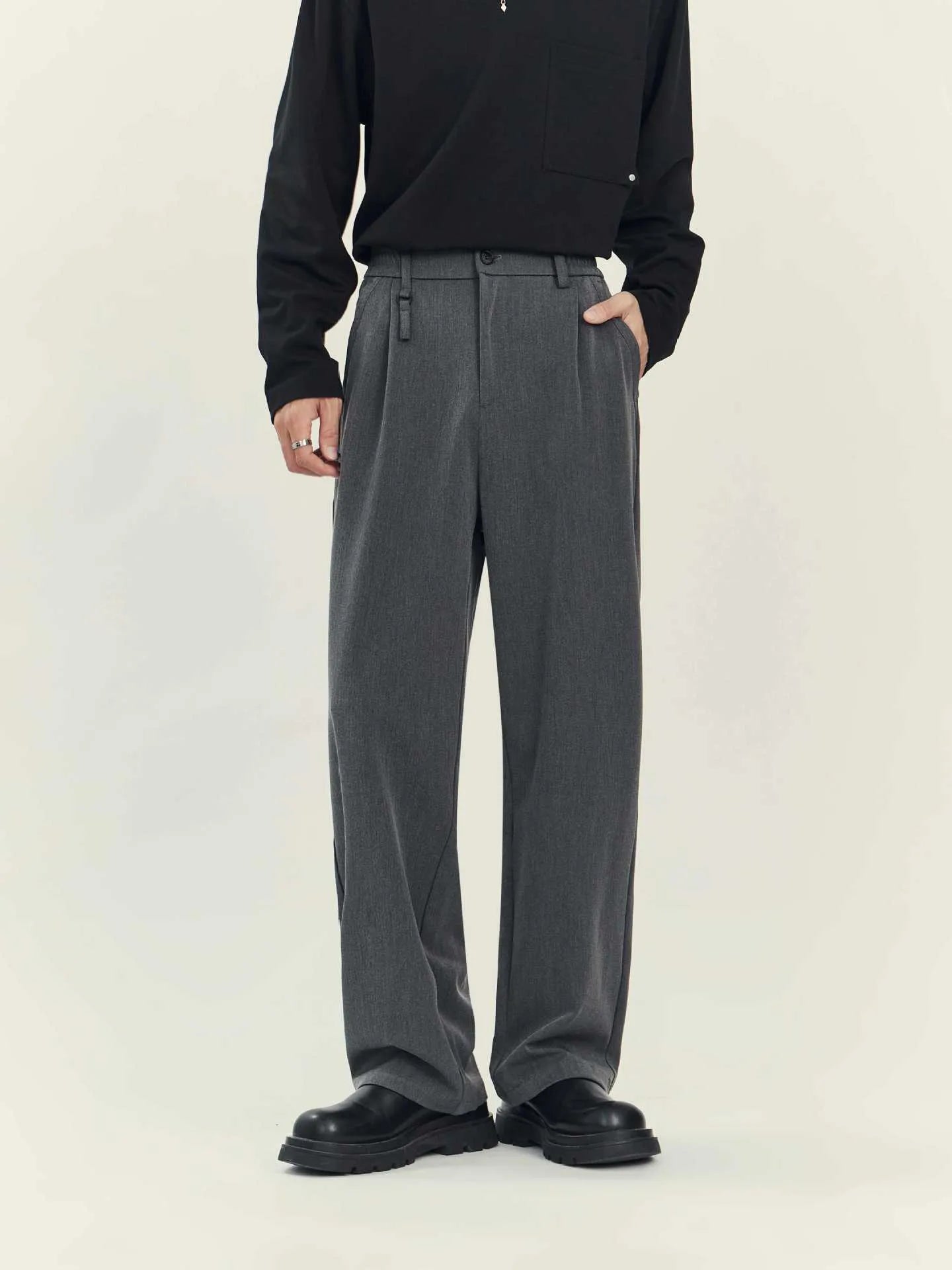 Man wearing loose straight-leg black business casual trousers made from polyester blend fabric.