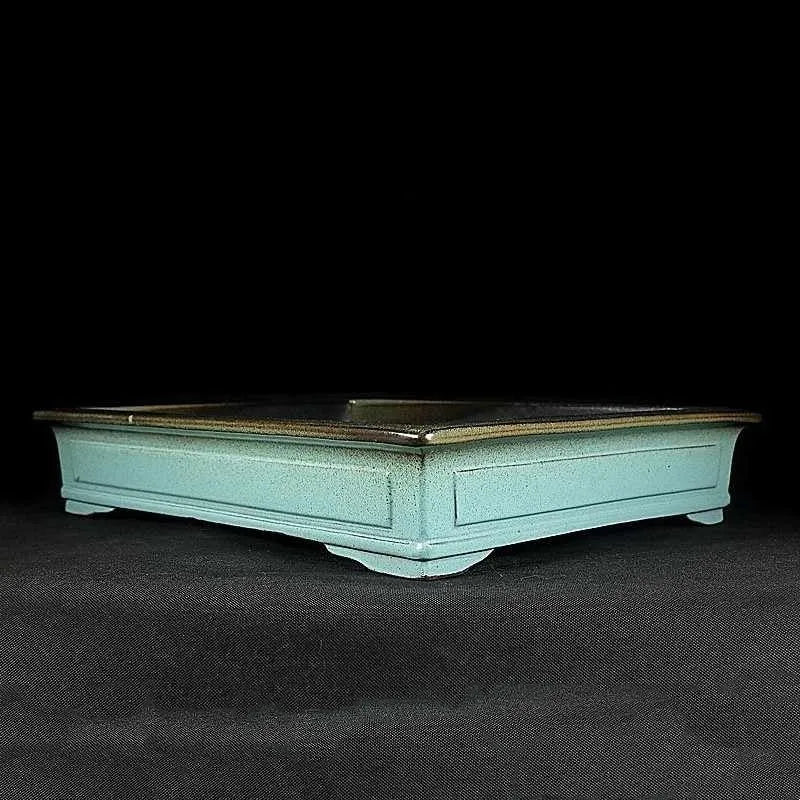 Green handmade ceramic bonsai pot with retro crackled glaze finish on wooden surface